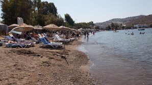A beach with sun loungers and umbrellas, a sandy shore, and a calm sea. - Metin's Gumusluk (Bodrum)