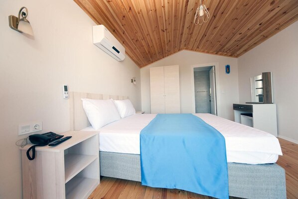A bedroom with a wooden ceiling, a bed with a blue blanket, a bedside table with a phone, and a wardrobe. - Metin's Gumusluk (Bodrum)