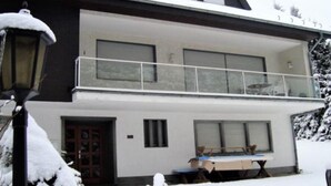 A modern two-story house with a balcony, large windows, and a snow-covered exterior. - Ferienhaus Beja (Winterberg)