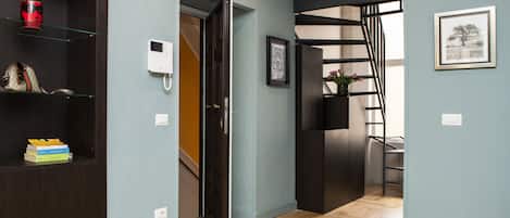 A modern interior with a wooden floor, a dark-colored bookshelf, and a door leading to another room.