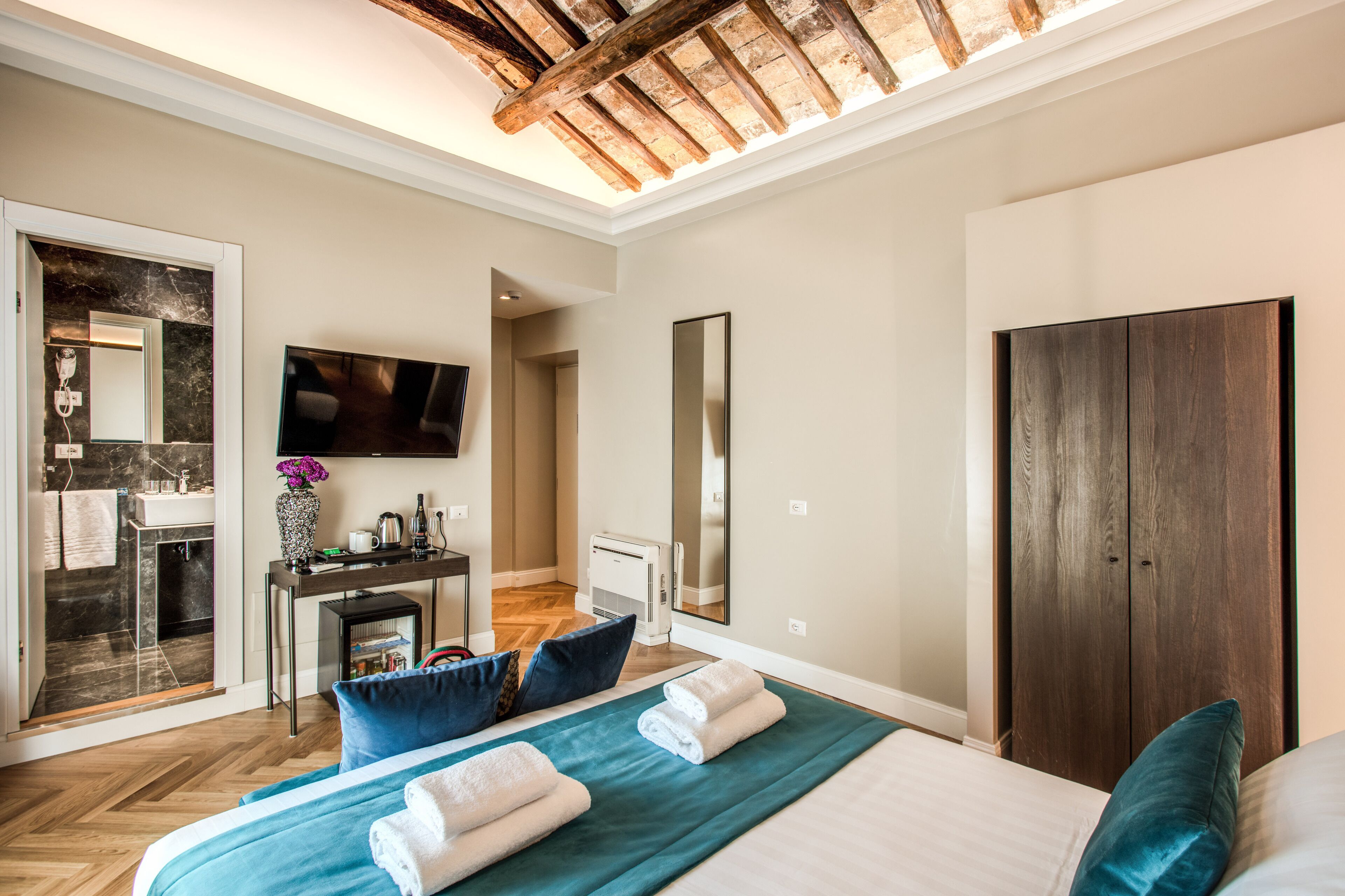 Une chambre d’hôtel avec un lit, un bureau, un miroir, une armoire et un téléviseur.