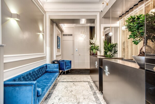 A reception area with a blue sofa, a reception desk, and a potted plant.
