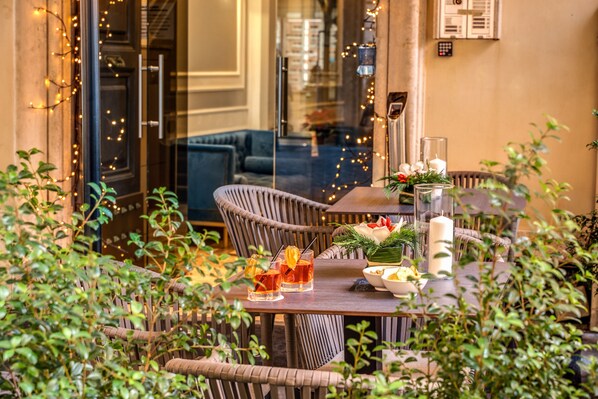 An outdoor dining area with wicker chairs, a wooden table, and string lights.