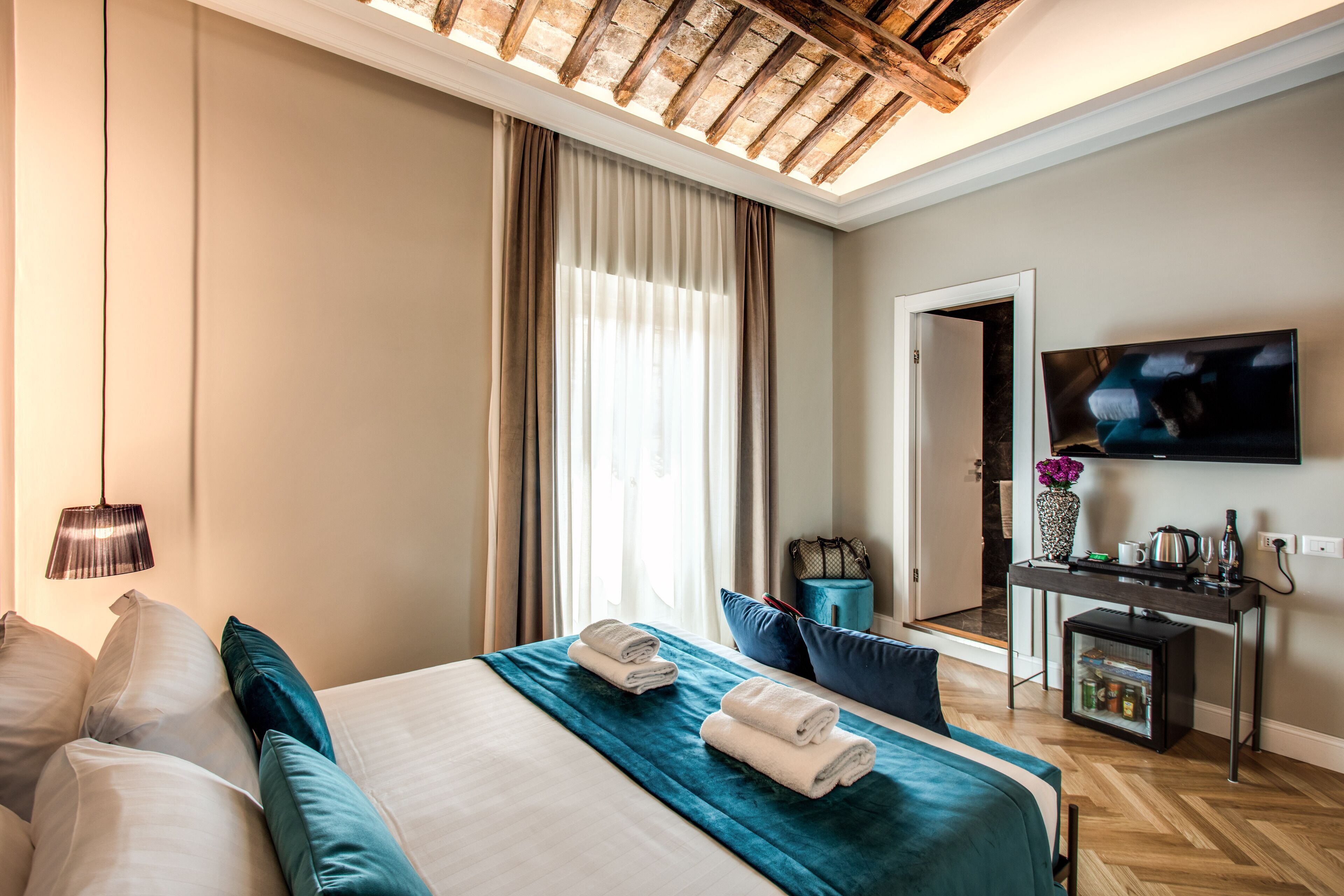A hotel room with a bed, a desk, a TV, and a window with curtains.