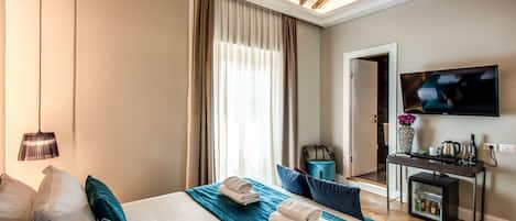 A hotel room with a bed, a desk, a TV, and a window with curtains.