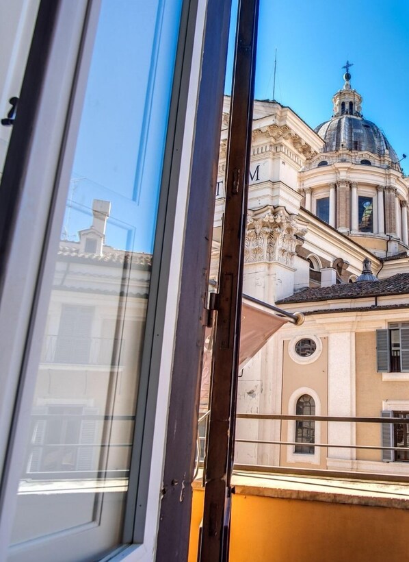 Vista a través d'una finestra d'un edifici d'arquitectura clàssica, amb cúpula i columnes.
