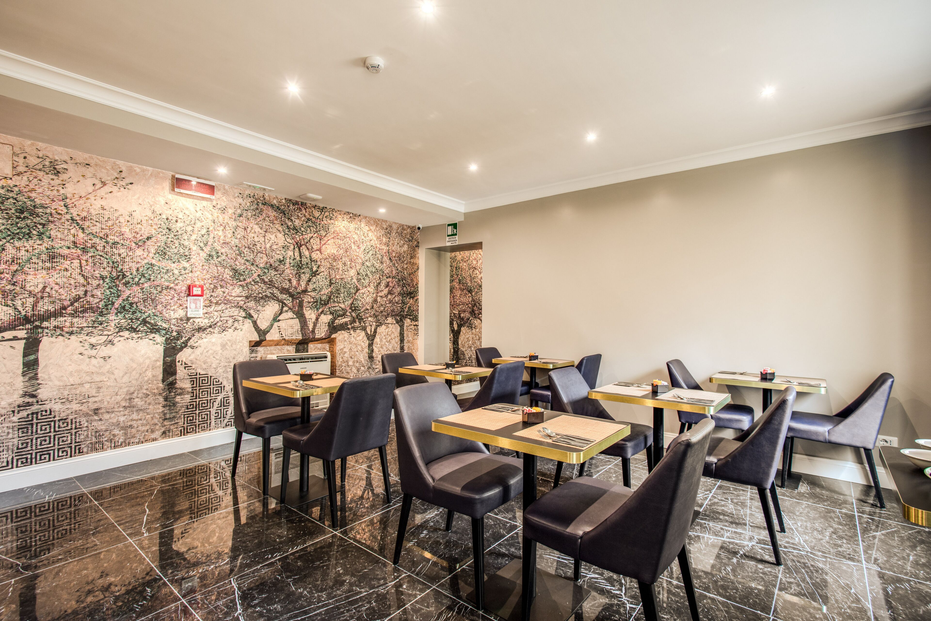 Ein Restaurant mit modernem Interieur, schwarze Ledersessel, Holztische und einer dekorativen Wandmalerei.