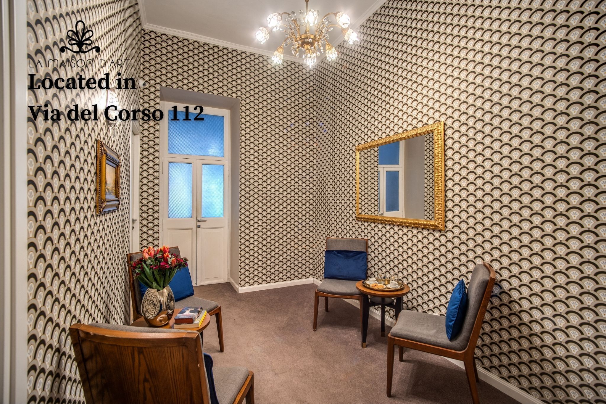 A room with patterned wallpaper, a chandelier, a mirror, and a view of Via del Corso 112.