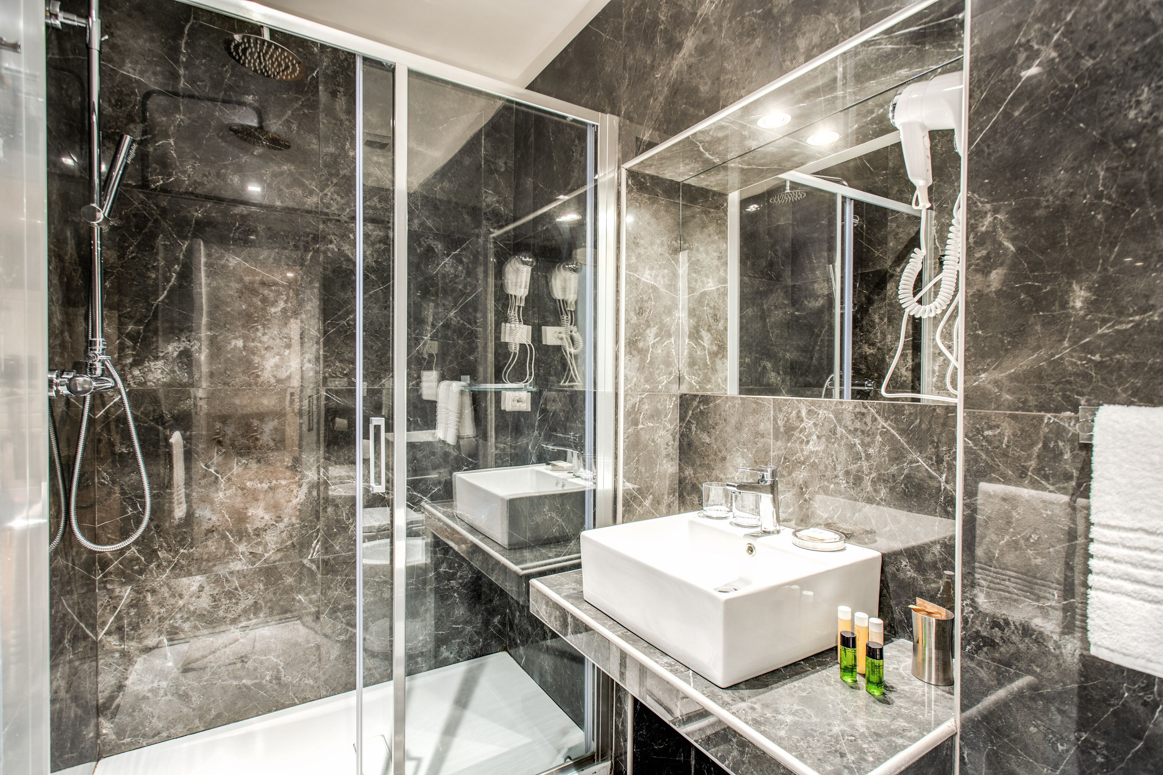 A modern bathroom with a glass-enclosed shower, a white sink, and a large mirror.