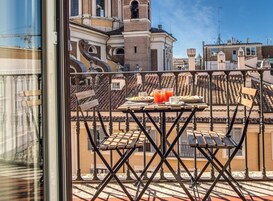 A balcony with a table set for breakfast, overlooking a cityscape with historic buildings.