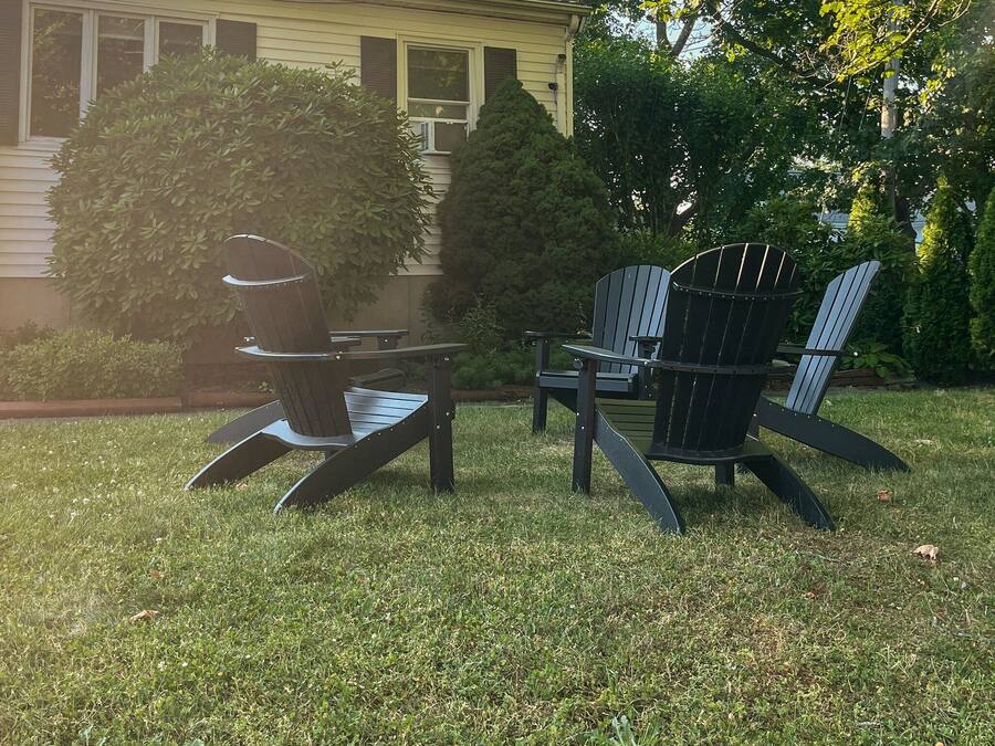 A lawn with two Adirondack chairs and a small table.