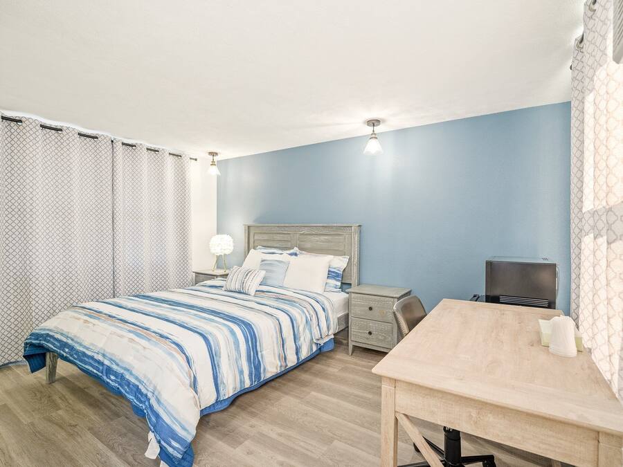 Ein Schlafzimmer mit Bett, Nachttischen, Schreibtisch und Fernseher.
