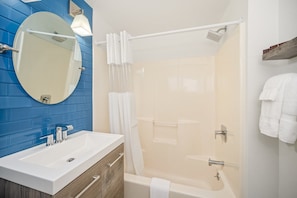 Bathroom features a large mirror, sink, cabinetry, shower, and bathtub.