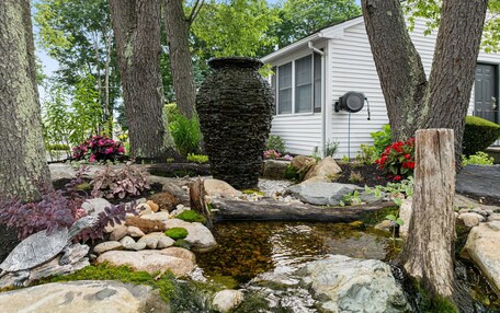 A garden with a pond, rocks, and a turtle statue.