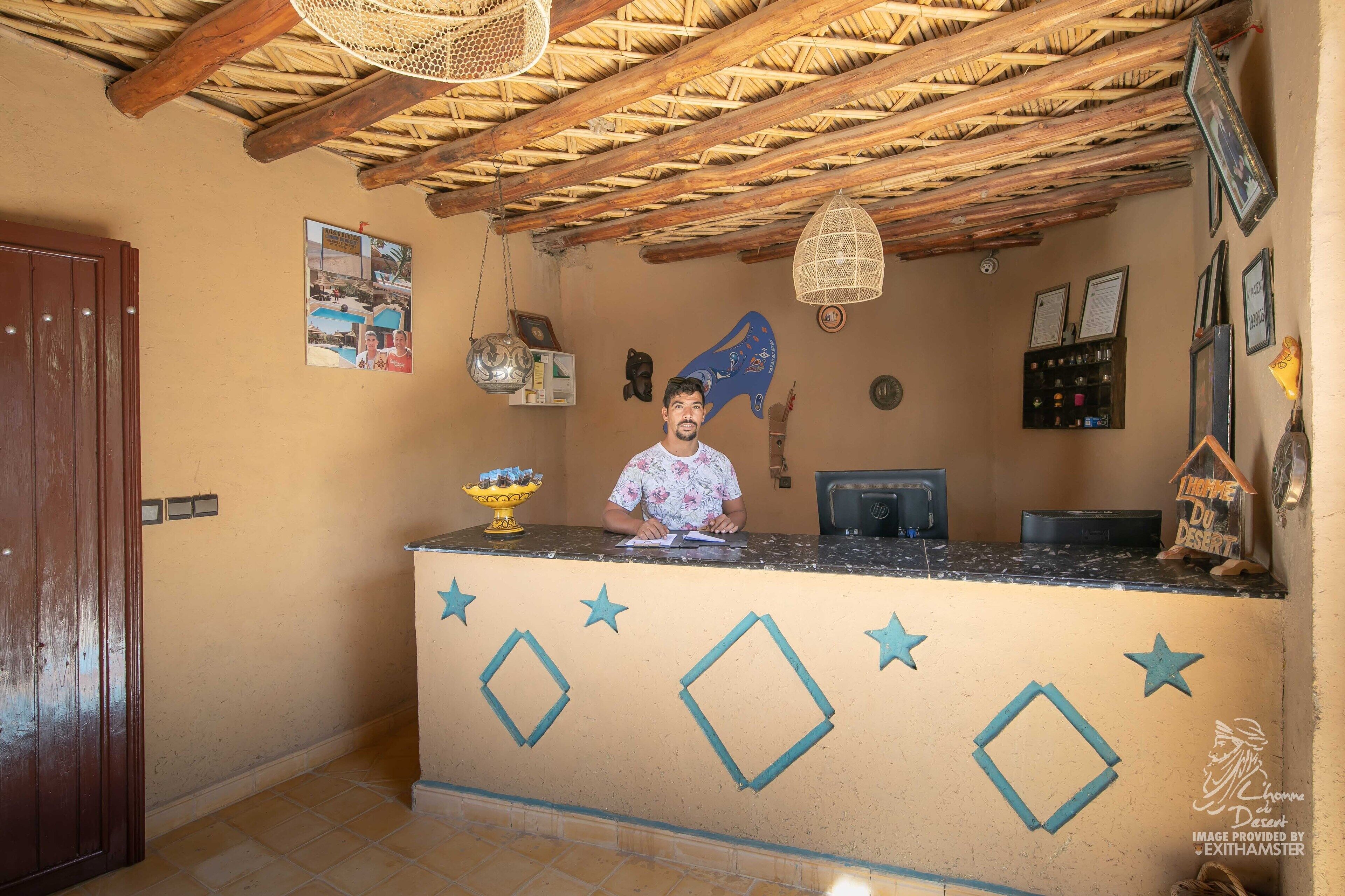 A reception desk with a wooden ceiling, framed pictures, and a decorative wall with stars and a fish.