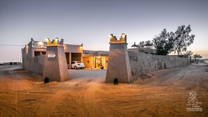 A desert-themed hotel entrance with a car parked inside. - L'Homme du Désert (Taouz)