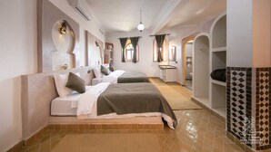 A hotel room with two beds, a bathroom, and a hallway. - L'Homme du Désert (Taouz)