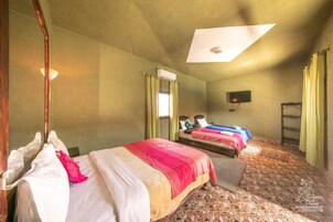 Habitación de hotel con dos camas, televisión y ventilador de techo.