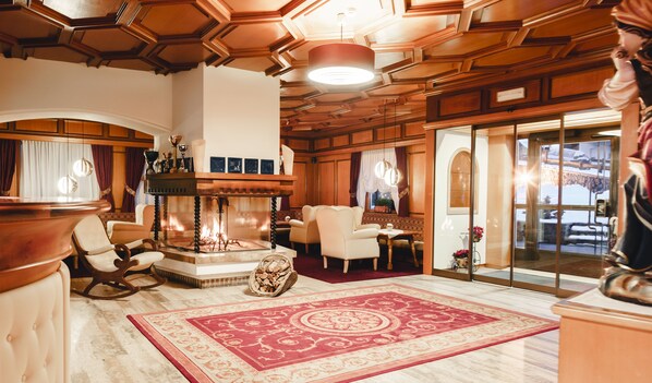 Ein luxuriöses Zimmer mit Kamin, komfortablen Sitzmöglichkeiten und einem großen roten Teppich.