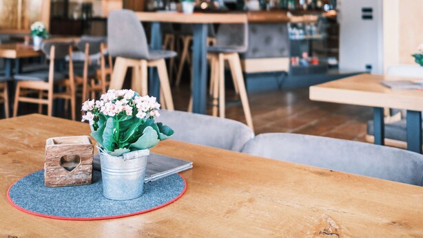 L’intérieur chaleureux du restaurant est agrémenté de poutres en bois au plafond, de luminaires suspendus et d’un bar situé au fond de la salle.