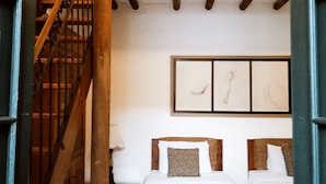 Une chambre avec deux lits, un escalier en bois et un luminaire au plafond.