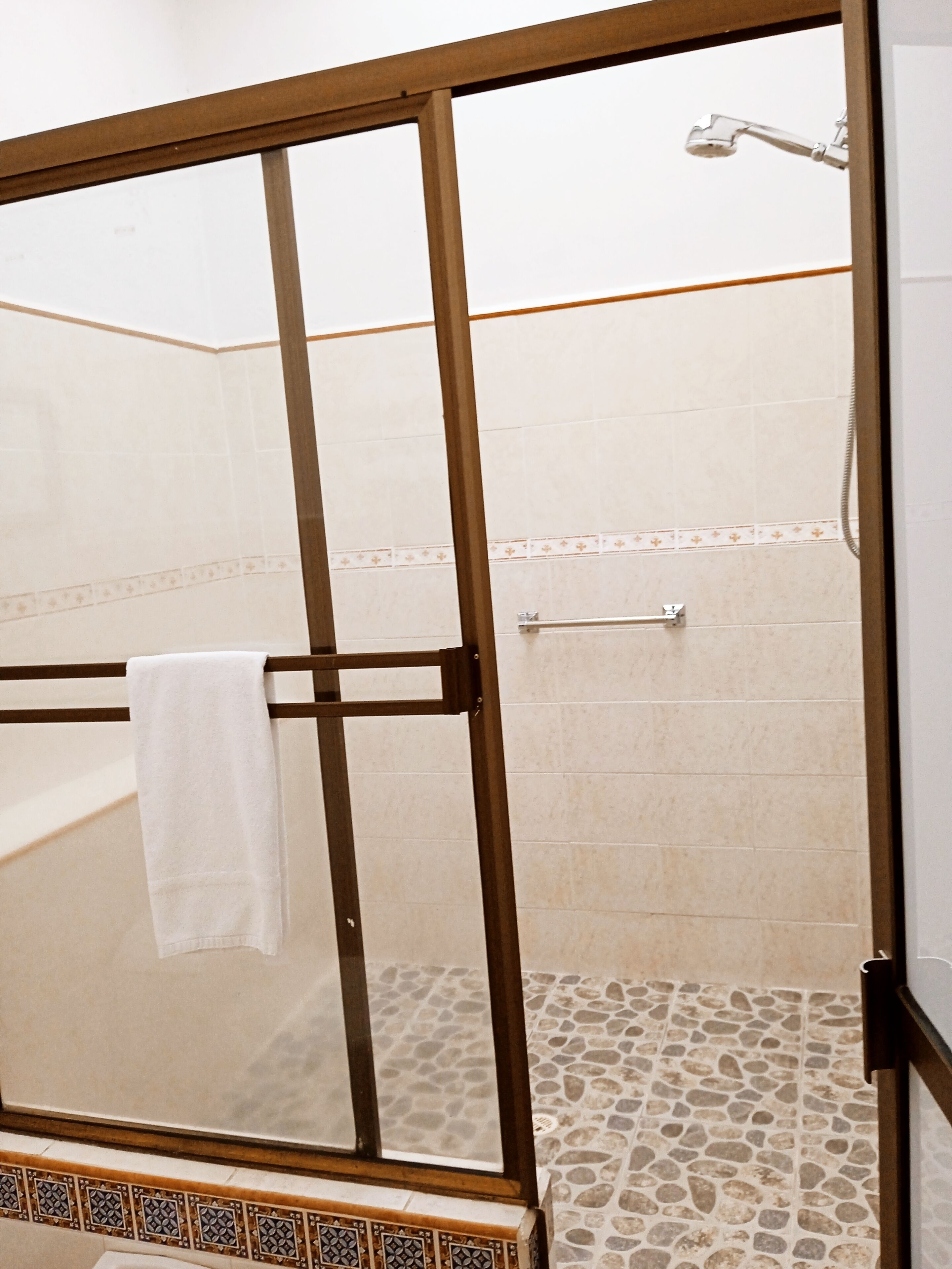 A glass-enclosed shower area with a white towel hanging on the door handle.