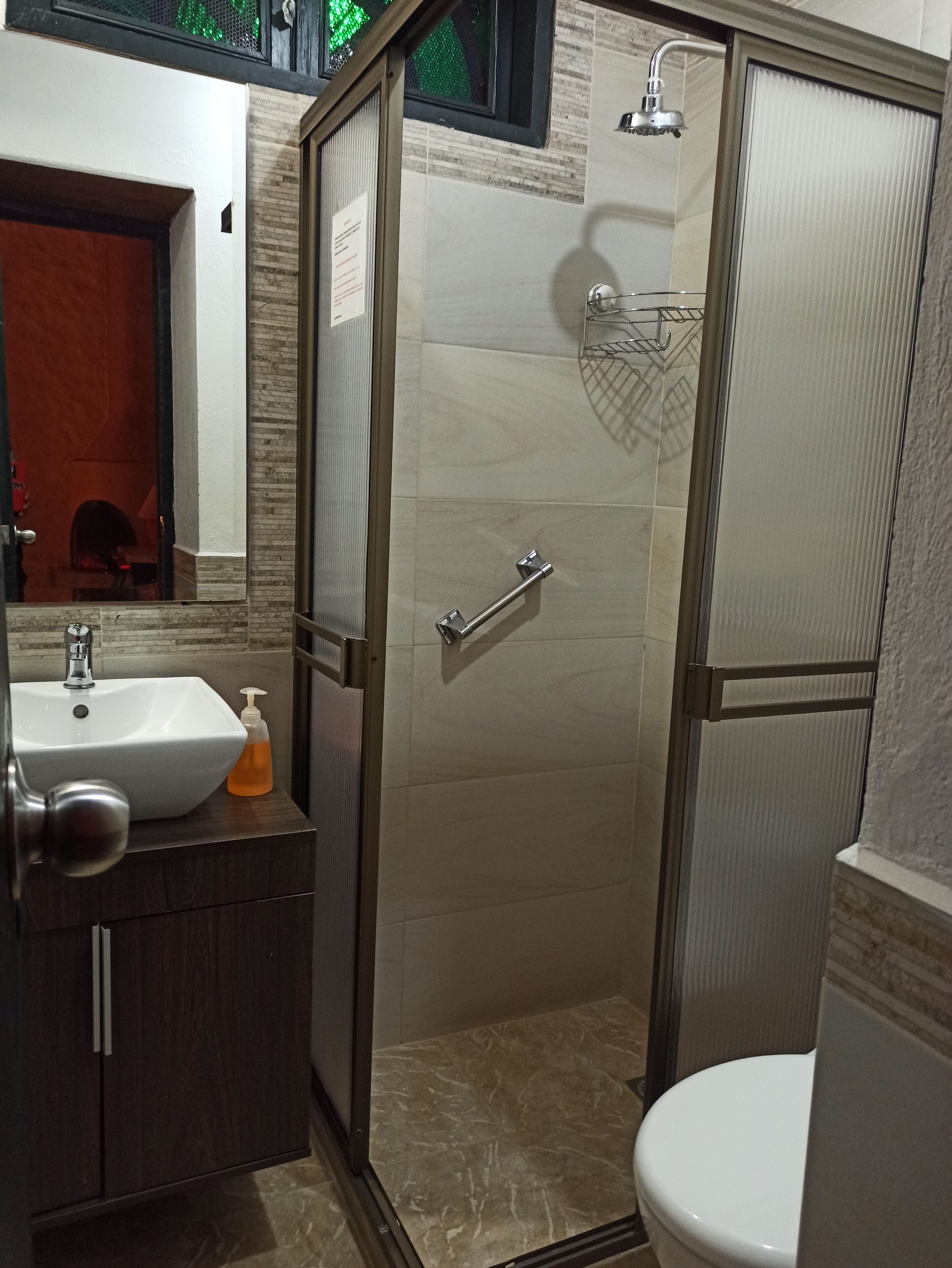 A bathroom with a shower, a sink, and a toilet.