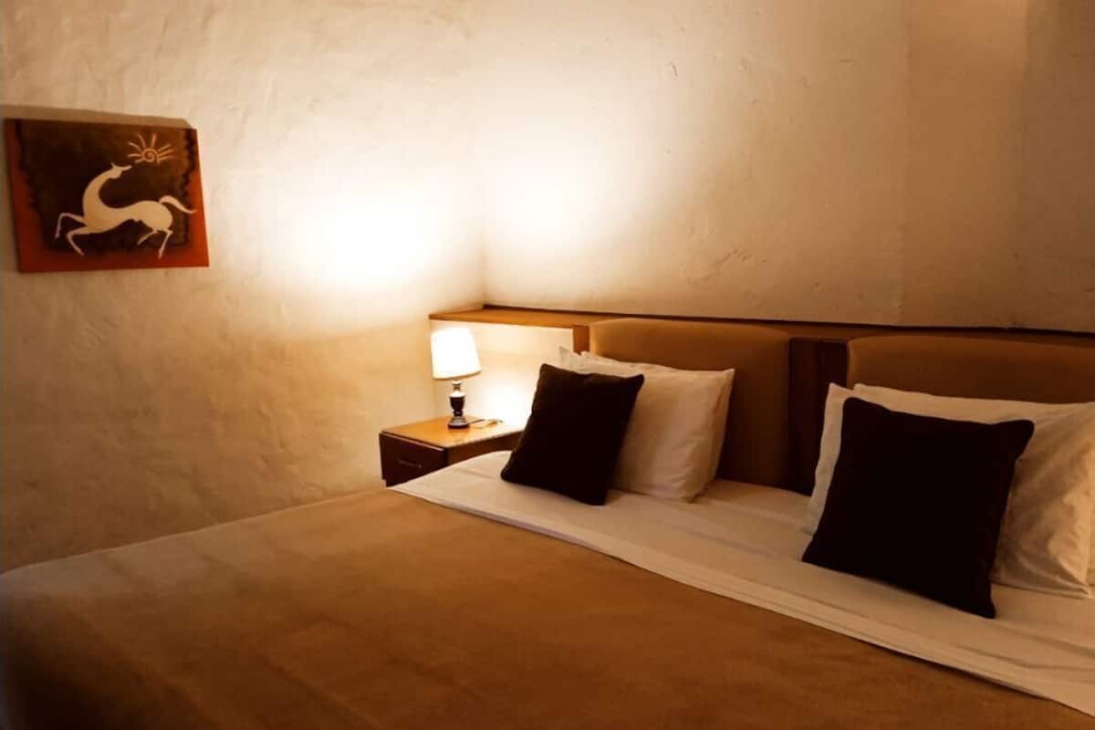Une chambre d’hôtel avec un lit, des oreillers, une table de chevet avec une lampe et un tableau au mur.