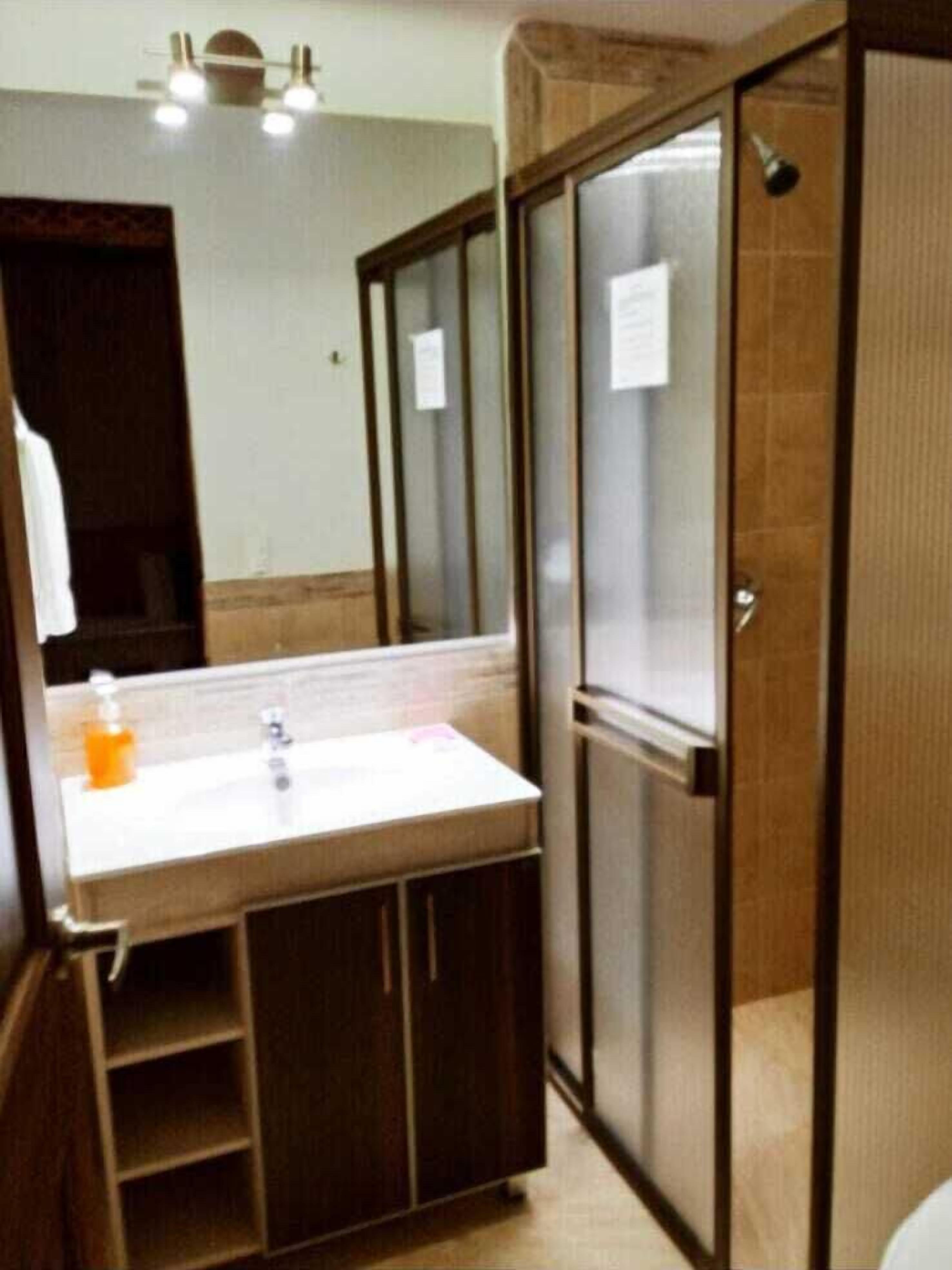 A bathroom with a wooden vanity, a mirror, and a sink.