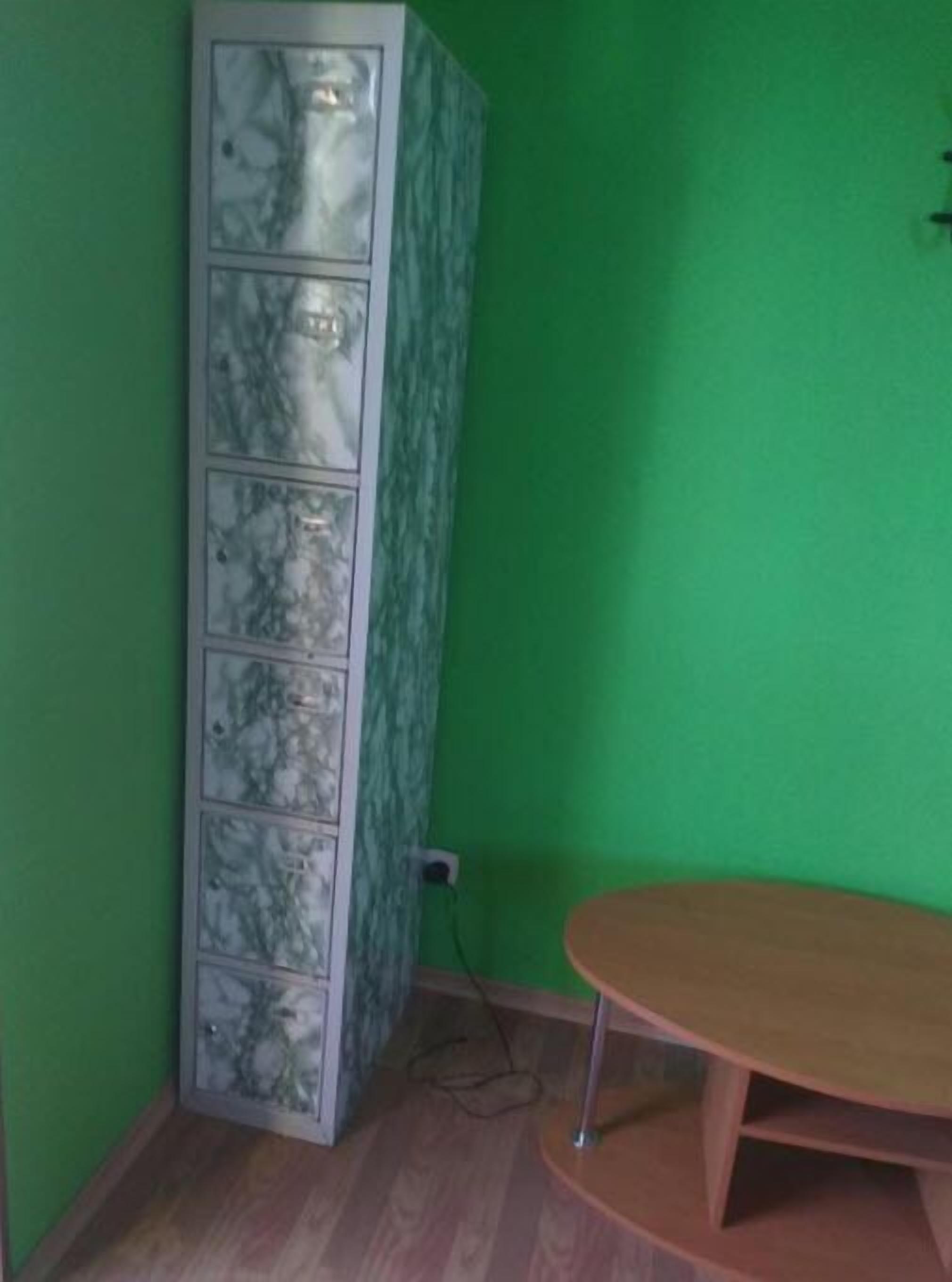 Una habitación con pared verde, un mueble con diseño de mármol y una mesa redonda de madera.