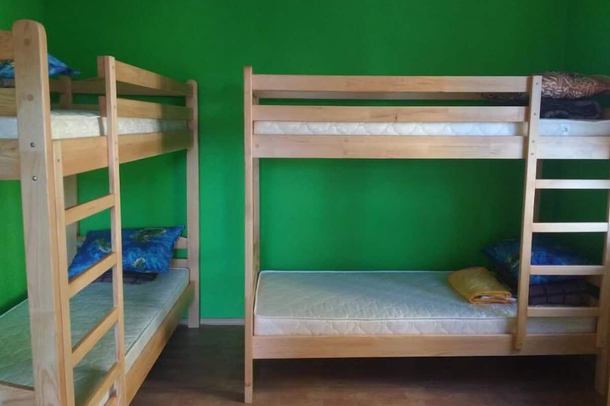 Quarto com beliches de madeira e paredes verdes.