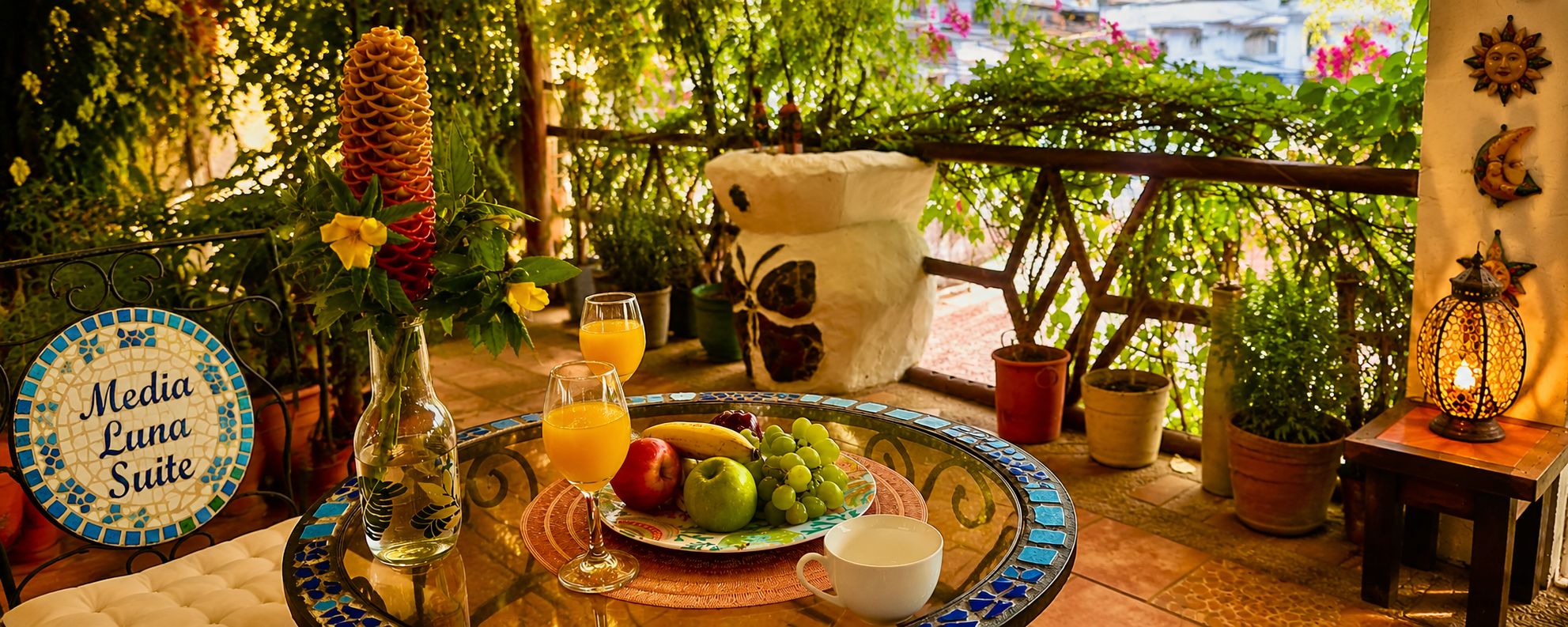 A table set with a fruit plate, glasses, a vase, and a sign reading 'Media Luna Suite'.