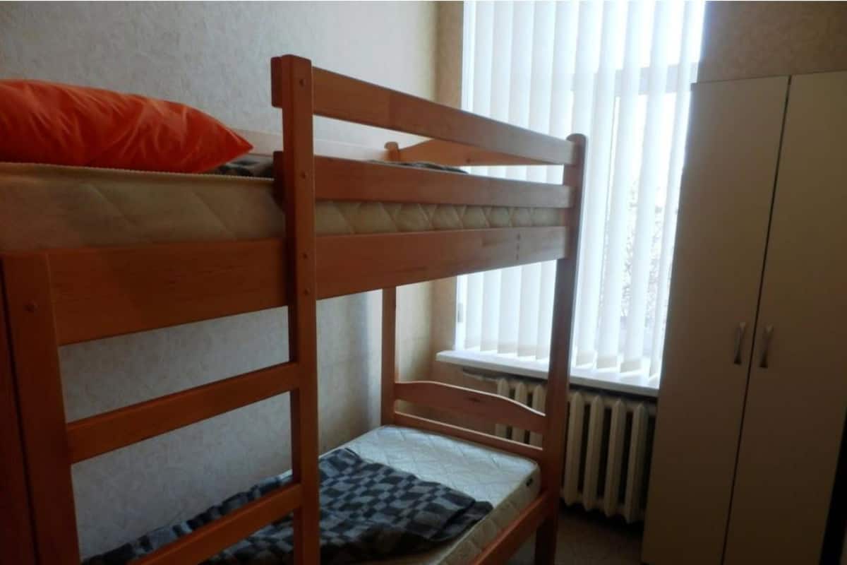A bunk bed in a room with a window and a radiator.