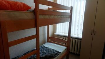 Un lit superposé dans une chambre avec une fenêtre et un radiateur.
