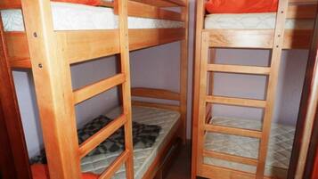 Une chambre avec deux lits superposés en bois, chacun étant équipé d’un matelas et d’oreillers.
