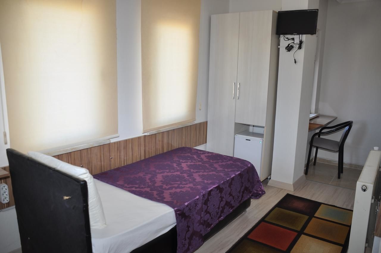 A bedroom with a bed, a wardrobe, a desk, and a television.