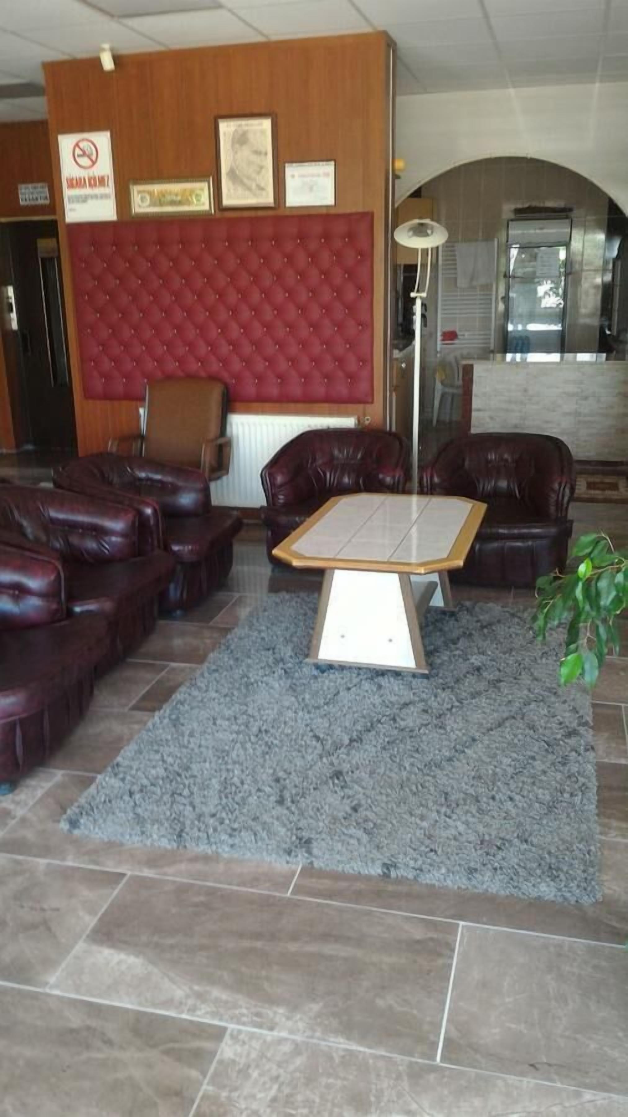 Eine Lobby mit Ledersofas, einem rot gepolsterten Bettvorhang, einem gefliesten Couchtisch und einem grauen Teppich.