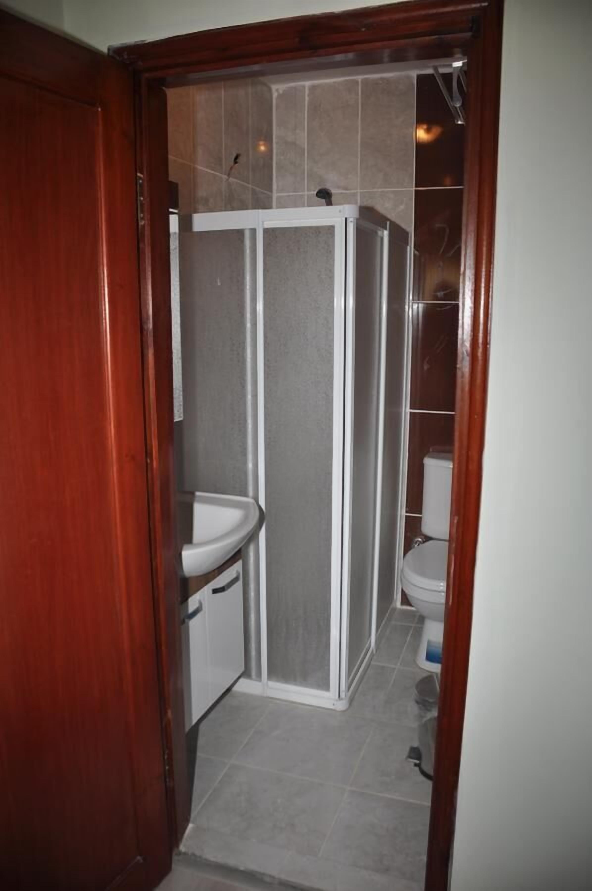 Un baño con cabina de ducha, lavamanos e inodoro.
