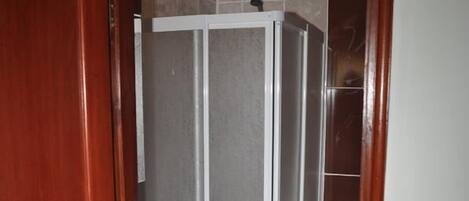 Un baño con cabina de ducha, lavamanos e inodoro.