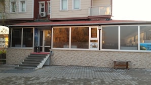 A two-story building with a covered entrance, a staircase leading to the ground floor, and a bench outside. - Gelibolu Kocoglu Hotel (Gallipoli)