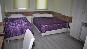 A room with two beds, each with a purple bedspread, a small white chair, and a cabinet. - Gelibolu Kocoglu Hotel (Gallipoli)