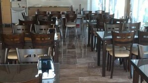 A restaurant with multiple tables and chairs, a tiled floor, and a yellow accent wall. - Gelibolu Kocoglu Hotel (Gallipoli)