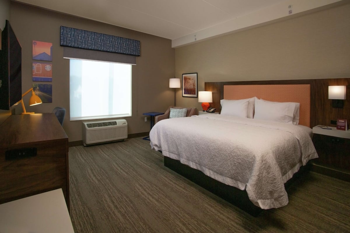Una habitación de hotel con una cama grande, lámparas de noche, un escritorio y una ventana.