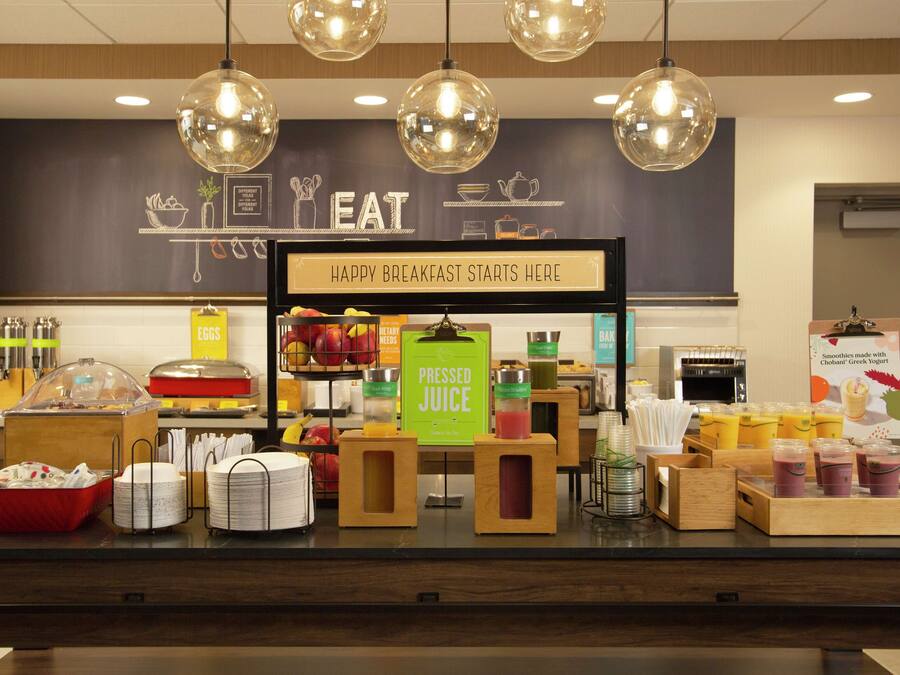 A breakfast buffet with various food items and beverages, including a sign that says "HAPPY BREAKFAST STARTS HERE".