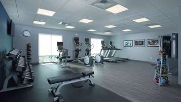 Uma academia com diversos equipamentos de exercício, incluindo esteiras, bicicletas ergométricas e pesos livres.