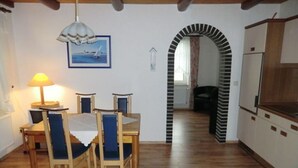 Un'area pranzo con un tavolo e sedie in legno, una lampada a sospensione e un quadro appeso al muro.