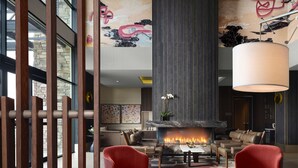 A modern lounge area with a fireplace, red chairs, and a large white table. - The Knoll Hotel Napa Valley, Tapestry Collection by Hilton (Napa)