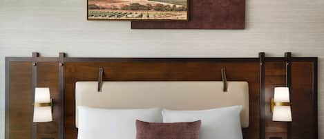 Habitación de hotel con una cama grande, dos mesitas de noche, un cabecero y un cuadro colgado en la pared.