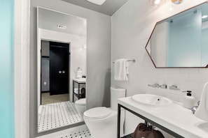 A modern bathroom with a white sink, mirror, and toilet.