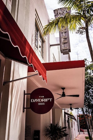 A building with a red awning, a sign reading "DAYDRIFT," and a palm tree.